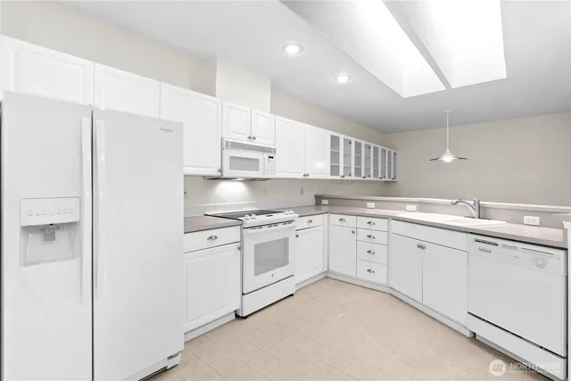 a kitchen with granite countertop white cabinets and white stainless steel appliances