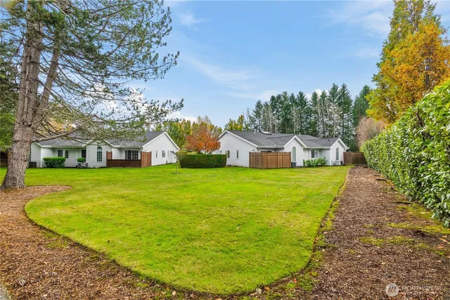 a view of a house with a big yard potted plants and large tree