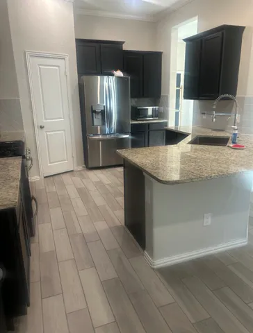 a kitchen with stainless steel appliances wooden floor and a refrigerator