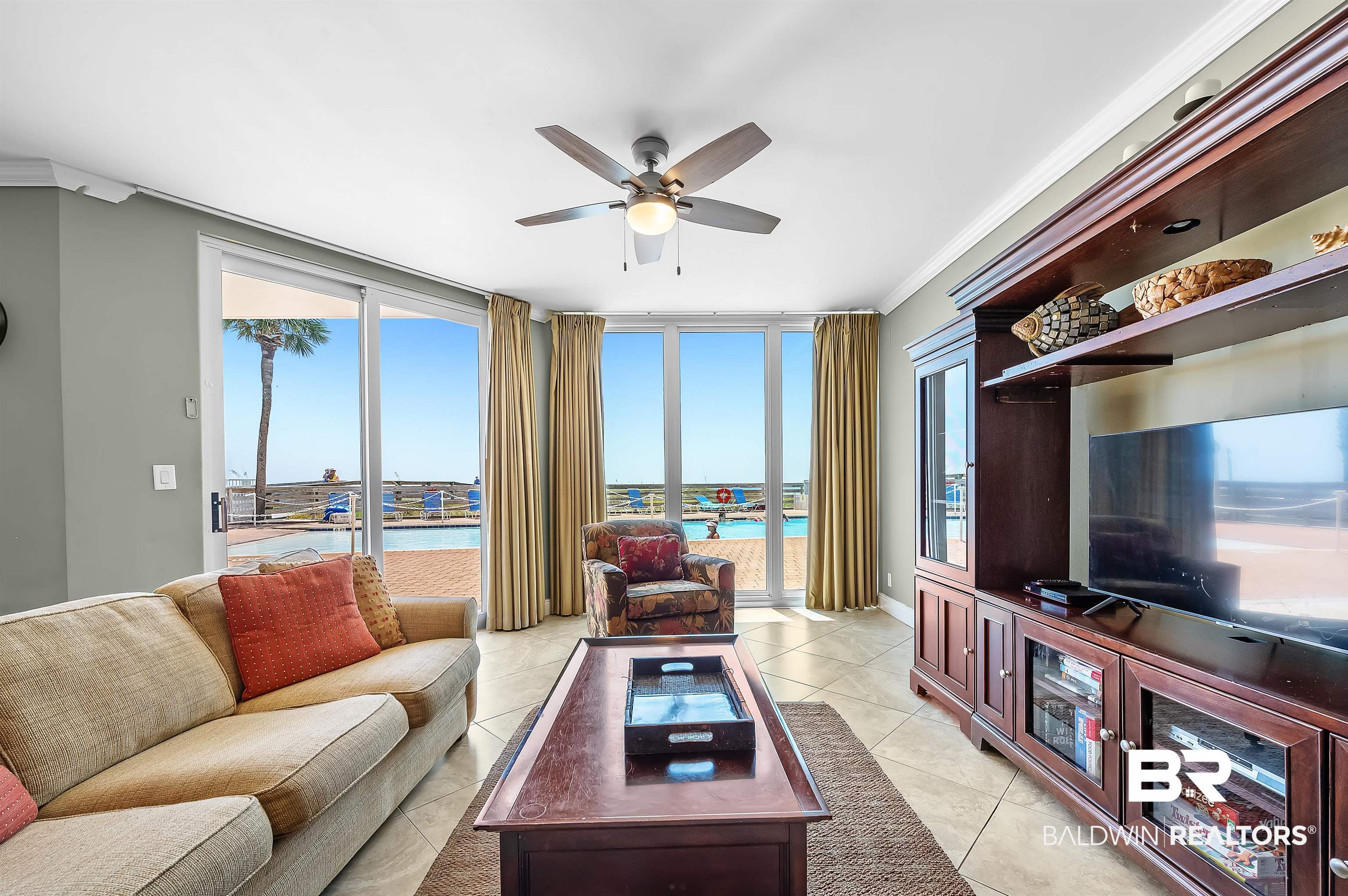16287 Perdido Key Drive, Unit 105 Pensacola, FL 32507 - Photo 18 of 66 Living area with multiple sliding glass doors opening to an outdoor patio with a pool beyond