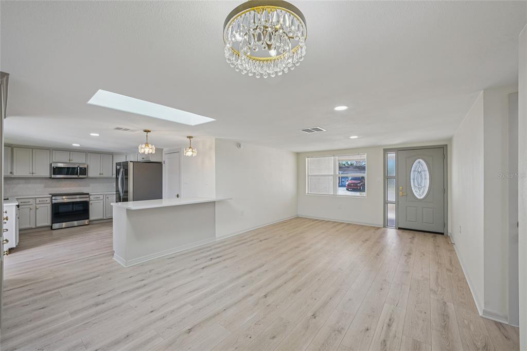 5753 10th Avenue New Port Richey, FL 34652 - Photo 7 of 46 an empty room with wooden floor a kitchen view and a window