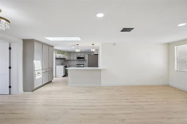 a view of open kitchen with white cabinets and wooden floor