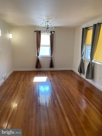 a view of an empty room with window and wooden floor