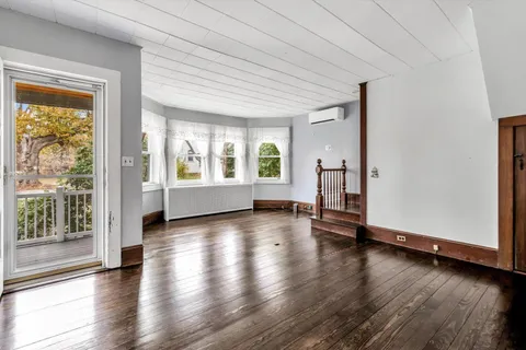 an empty room with wooden floor fireplace and windows