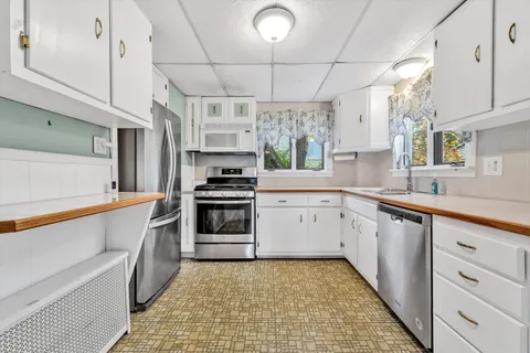 a kitchen with stainless steel appliances white cabinets and a stove top oven