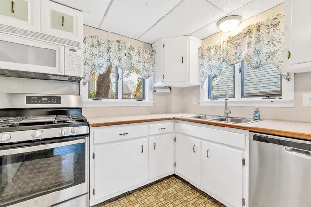 a kitchen with stainless steel appliances white cabinets and a stove top oven