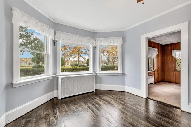 a view of an empty room with a window and wooden floor