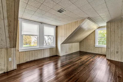 an empty room with wooden floor windows and exposed bricks