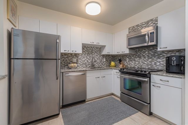 a kitchen with stainless steel appliances granite countertop a refrigerator sink stove and oven