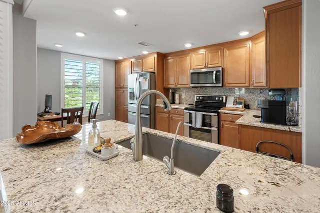 a kitchen with stainless steel appliances kitchen island granite countertop a stove a sink a microwave a refrigerator and cabinets