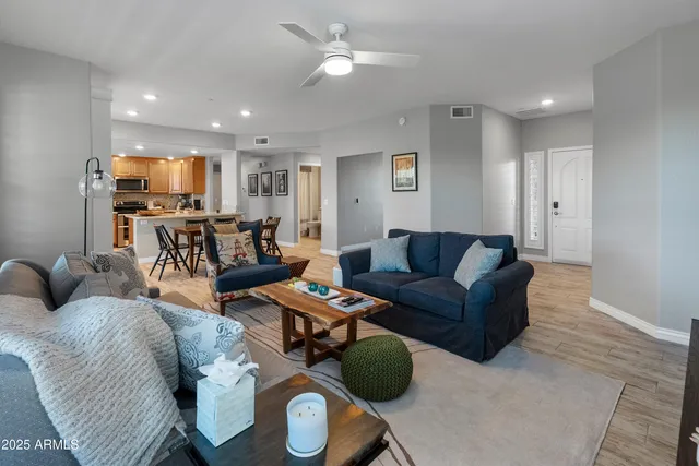a living room with furniture kitchen view and a wooden floor