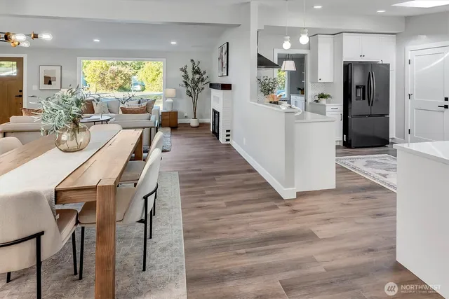 a kitchen with stainless steel appliances kitchen island granite countertop a table chairs refrigerator and a stove