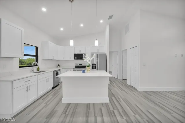 a large white kitchen with wooden floor and stainless steel appliances