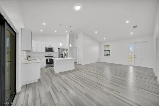 a view of kitchen with kitchen island wooden floors and stainless steel appliances