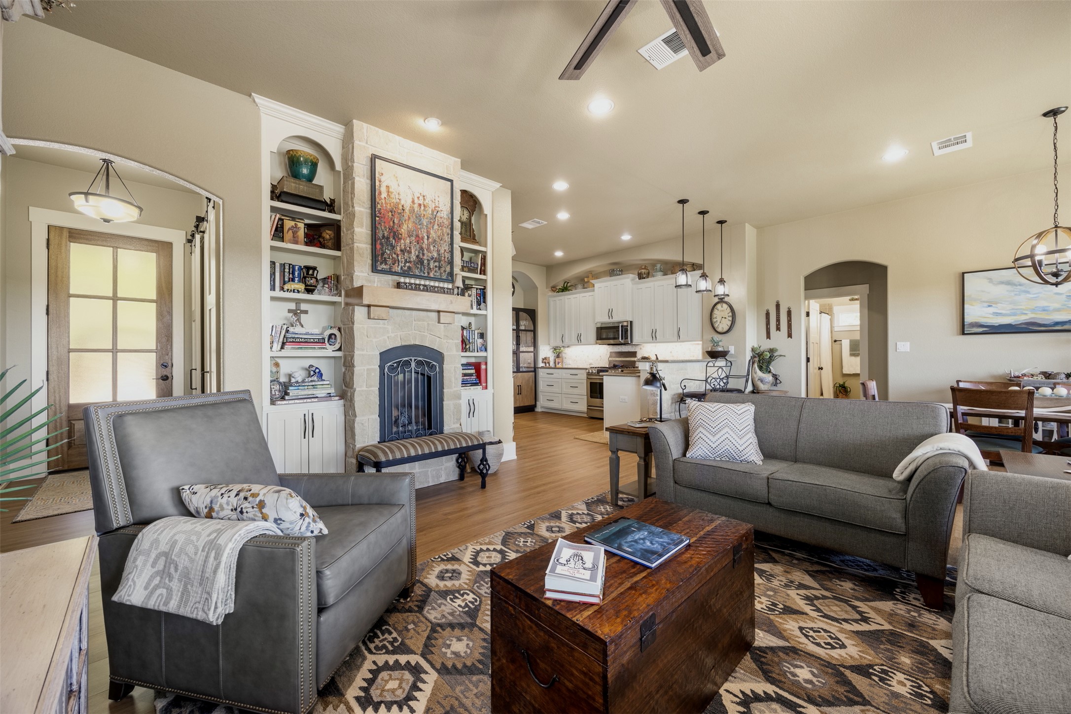 261 Barber Drive Wimberley, TX 78676 - Photo 7 of 37 Living room featuring arched walkways, a stone fireplace, dark wood-style flooring, ceiling fan, and recessed lighting
