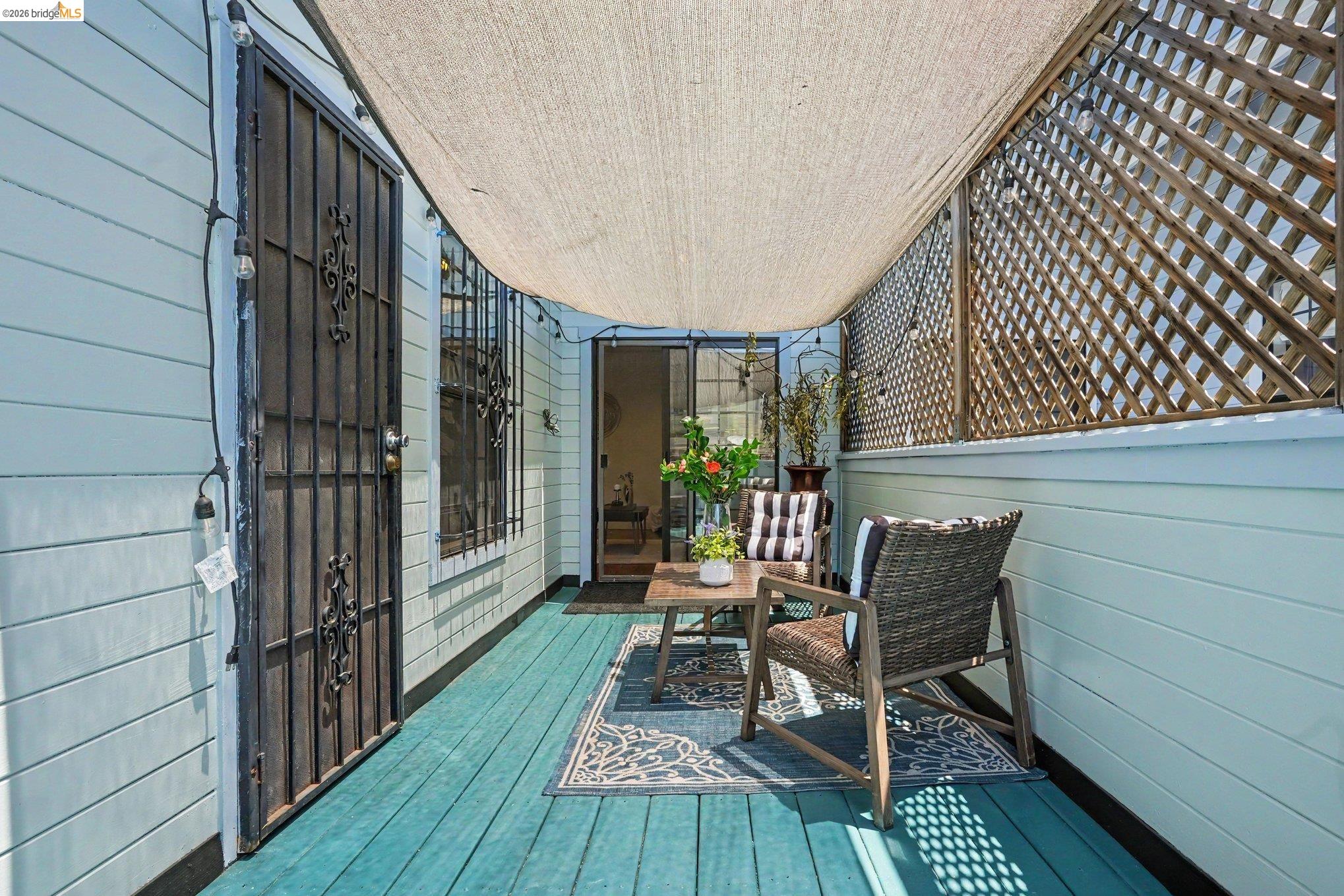 1433 Myrtle Street Oakland, CA 94607 - Photo 20 of 25 Covered patio area featuring a teal wood-finish deck, a sliding glass door entry, and a decorative security screen door