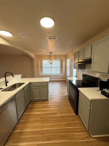 a large kitchen with stainless steel appliances granite countertop a sink and dishwasher a stove top oven with wooden floor