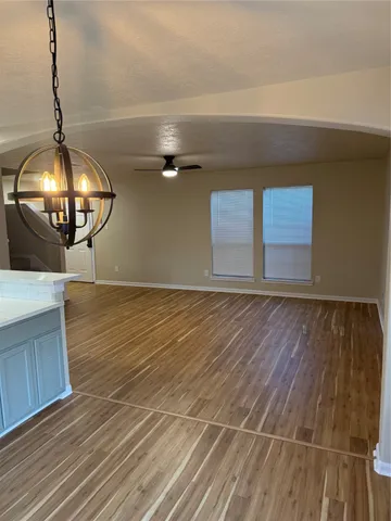 an empty room with wooden floor and chandelier