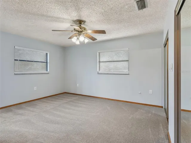 a view of an empty room with window and chandelier fan