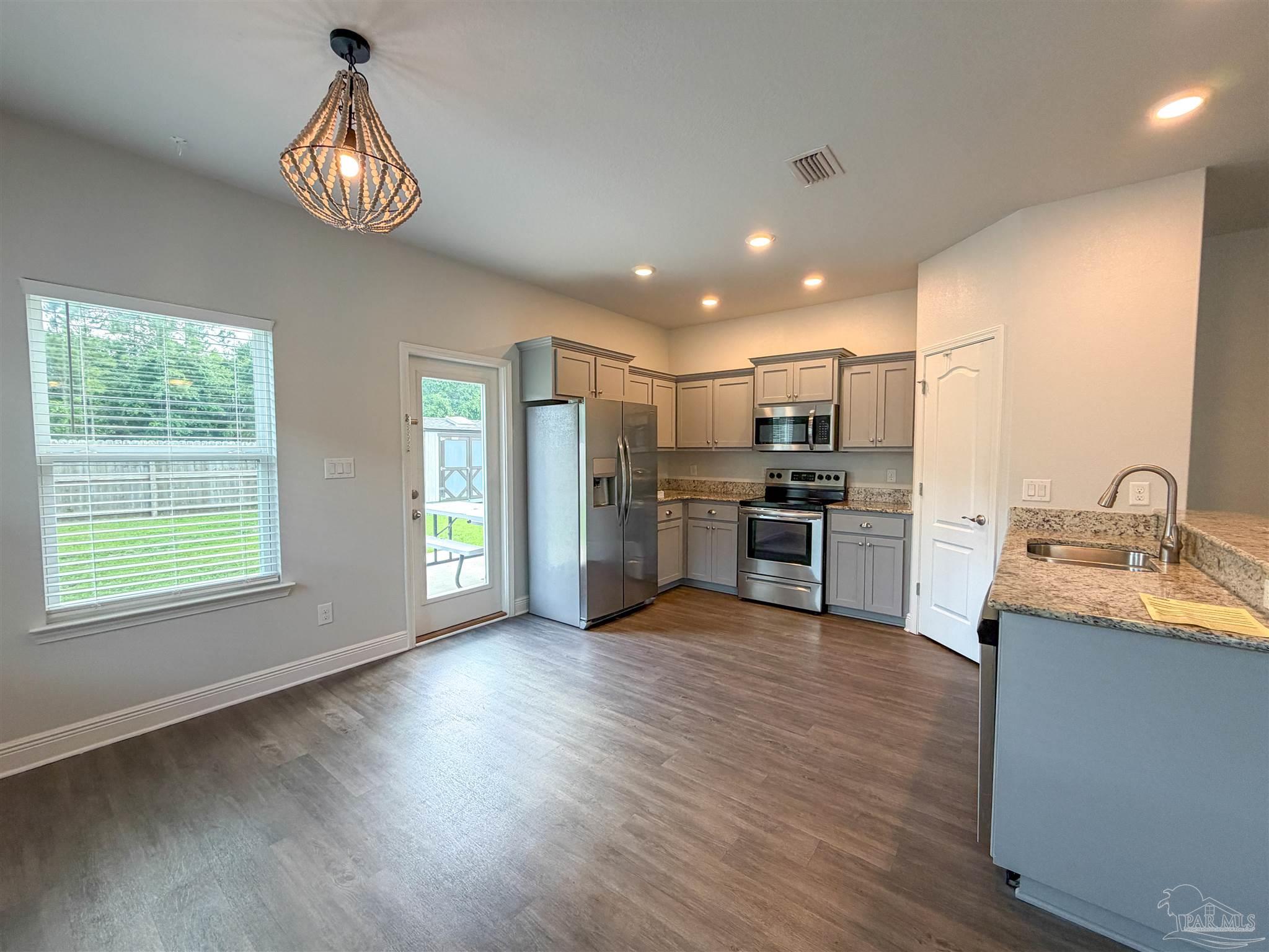 3613 Conley Drive Cantonment, FL 32533 - Photo 4 of 32 a view of a kitchen with stainless steel appliances granite countertop a sink dishwasher a refrigerator with wooden floor and cabinets
