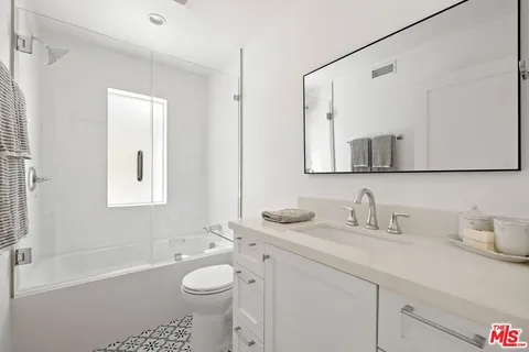a bathroom with a toilet a sink a mirror a bathtub and vanity