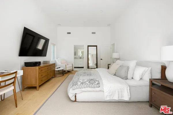 a spacious bedroom with a bed and a flat screen tv