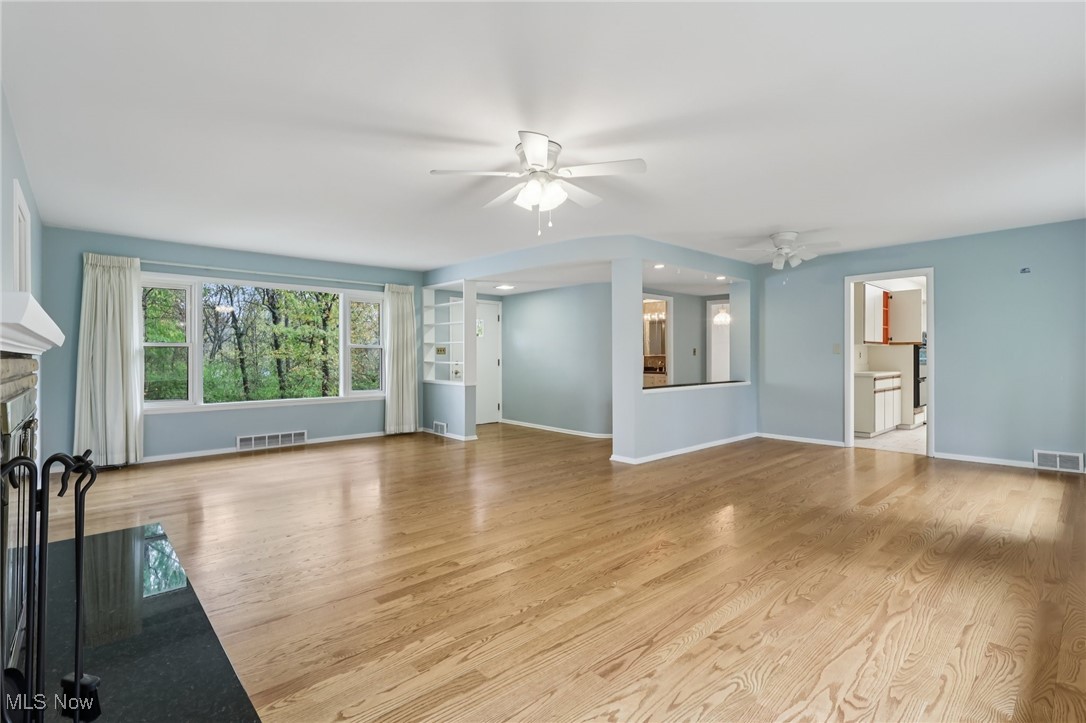 33300 South Woodland Road Cleveland, OH 44124 - Photo 9 of 50 Unfurnished living room featuring a ceiling fan, a fireplace, and light wood finished floors