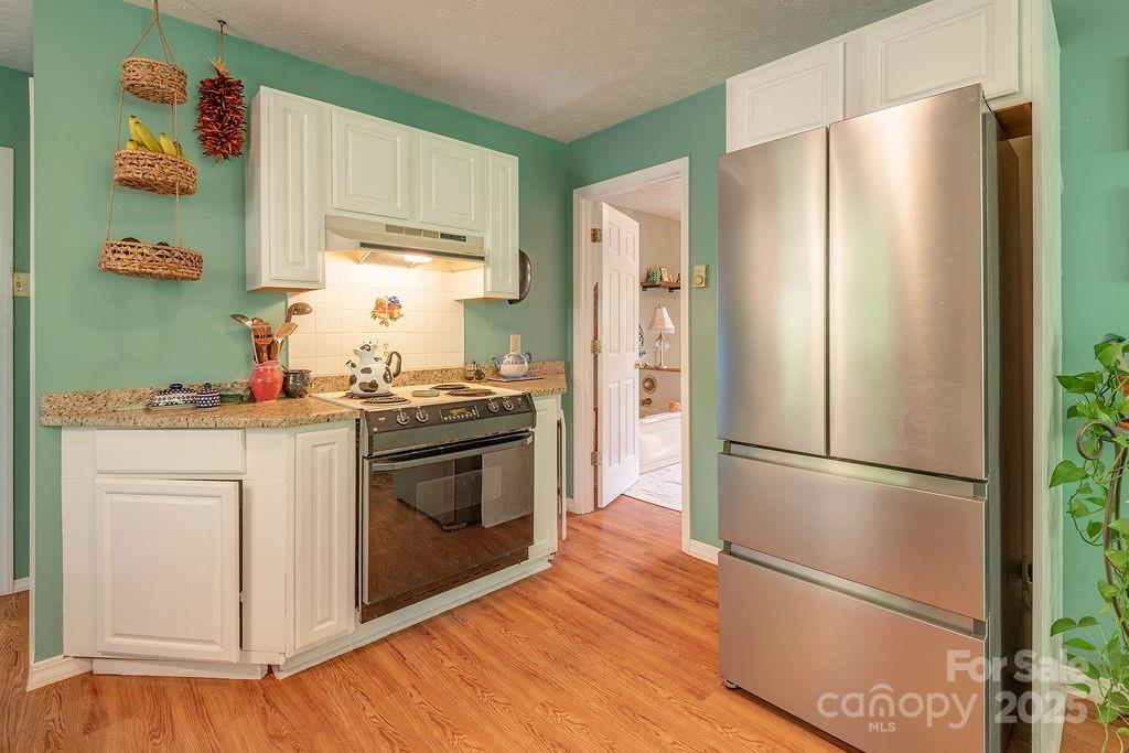 124 Beaverdam Loop Road Candler, NC 28715 - Photo 12 of 31 a kitchen with stainless steel appliances a refrigerator sink and wooden floor