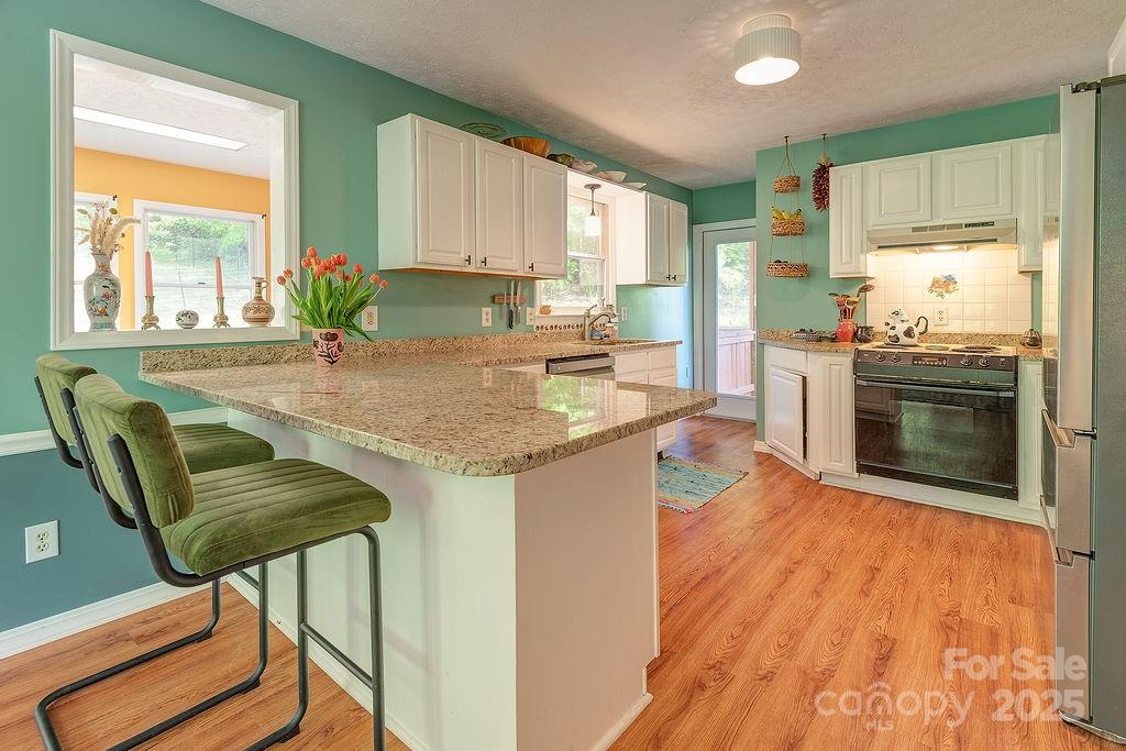 124 Beaverdam Loop Road Candler, NC 28715 - Photo 10 of 31 a kitchen with stainless steel appliances granite countertop a kitchen island hardwood floor sink stove and granite counter top