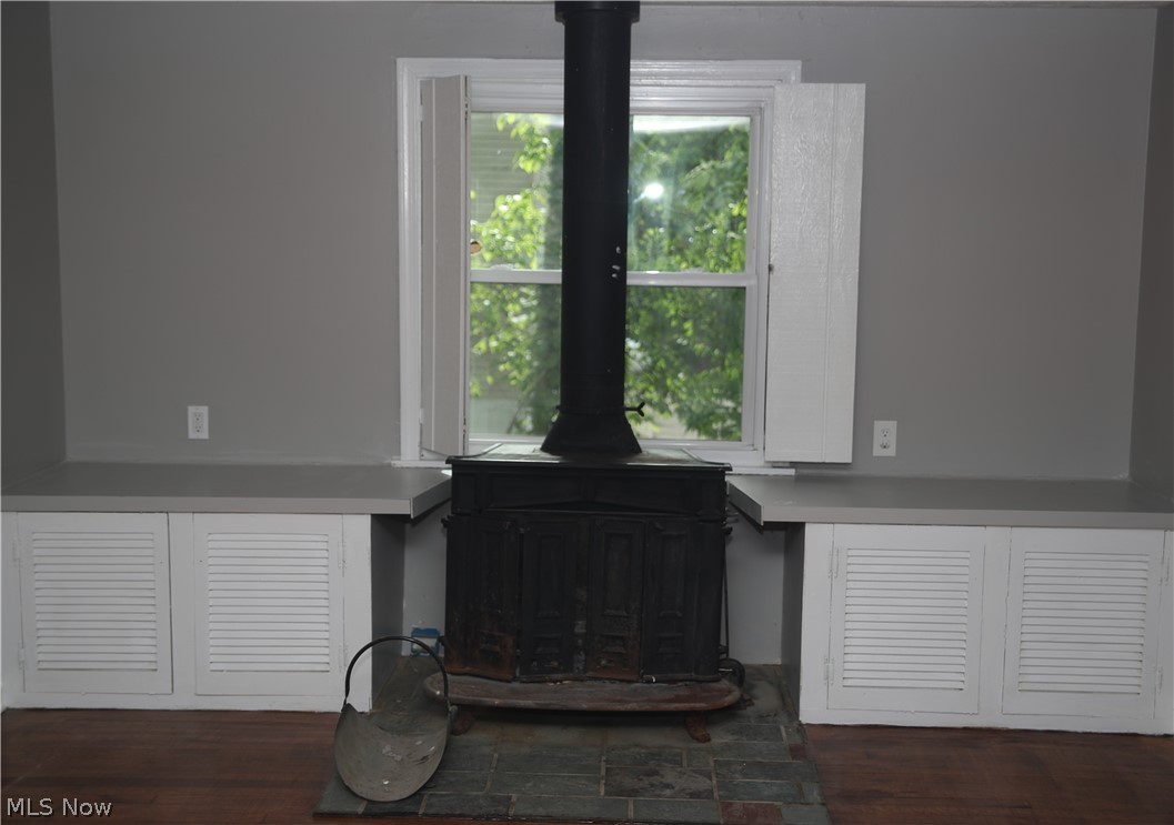 1087 Krumroy Road Akron, OH 44306 - Photo 3 of 23 Cast iron stove with a stone hearth, flanked by built-in cabinetry featuring louvered doors and a solid surface countertop