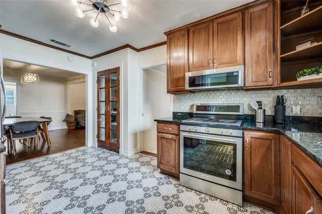 a kitchen with stainless steel appliances granite countertop a stove top oven a sink and a refrigerator
