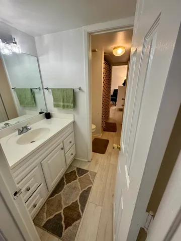 a bedroom with a bed and dresser with wooden floor