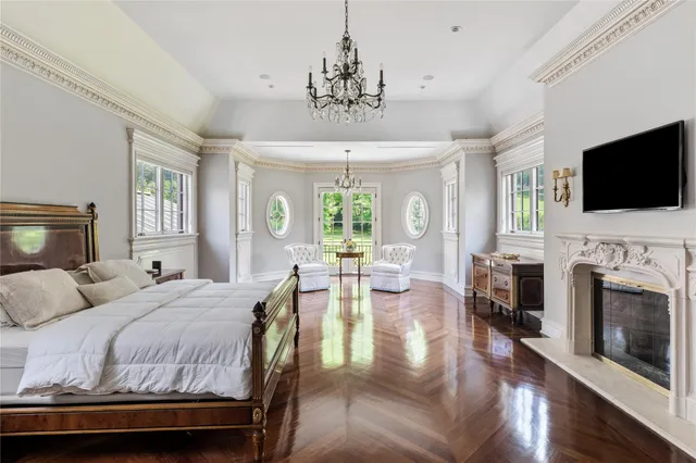 a bedroom with a bed a fireplace and a flat screen tv