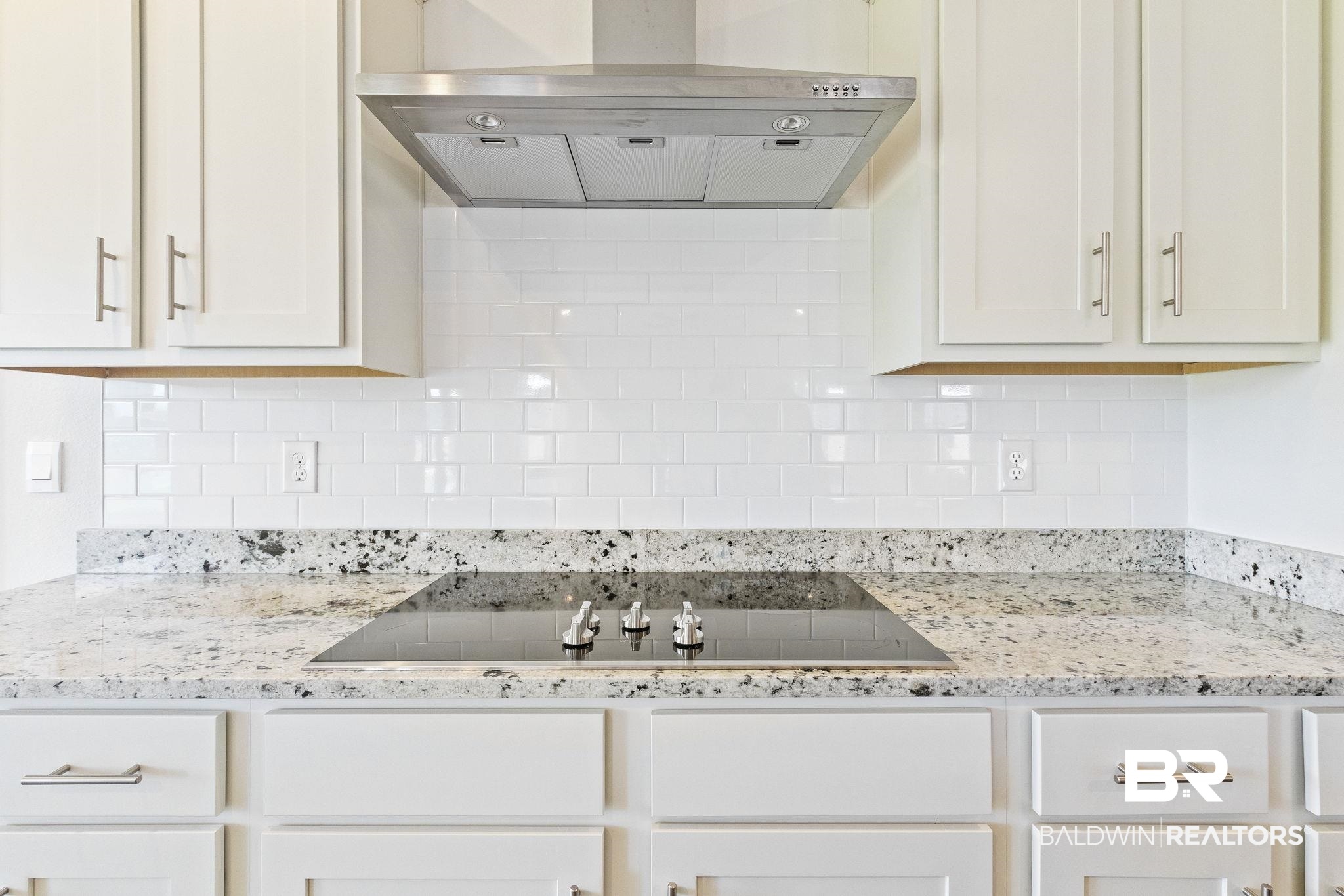 11303 Genuine Risk Circle Daphne, AL 36526 - Photo 25 of 100 Kitchen with extractor fan, decorative backsplash, black electric stovetop, and light stone counters