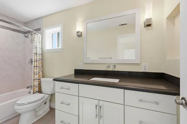 a bathroom with a granite countertop sink a toilet a vanity and shower
