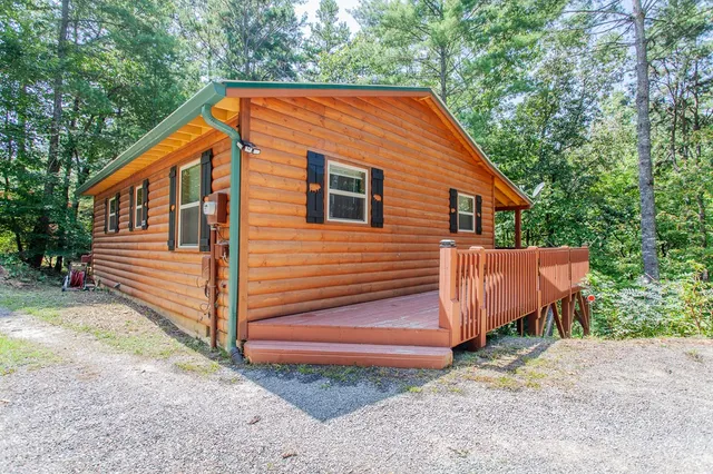 a backyard of a house with wooden floor and fence and trees
