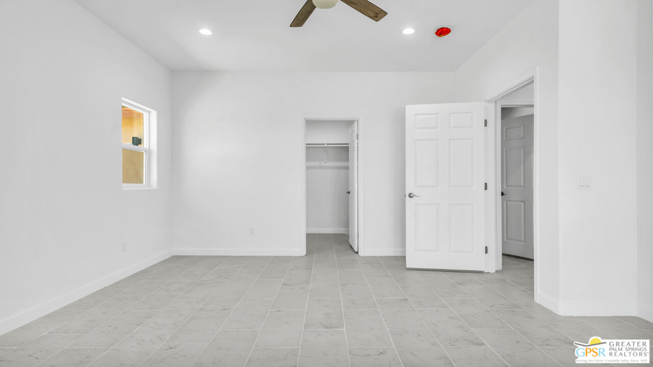7160 Olympic Road Joshua Tree, CA 92252 - Photo 19 of 58 an empty room with a ceiling fan and a window
