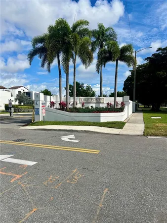 a view of a tall white house with a big yard and palm trees