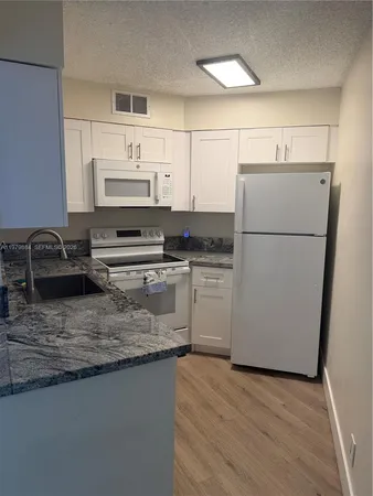 a kitchen with granite countertop a refrigerator a sink and white stove