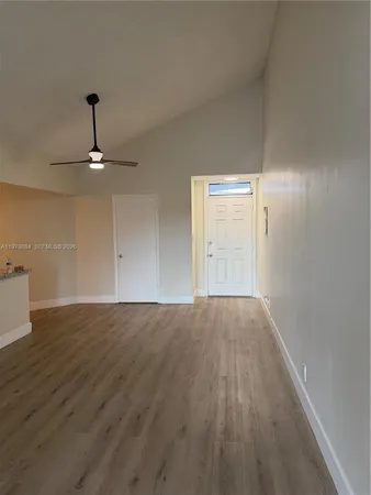 a view of empty room with wooden floor and fan
