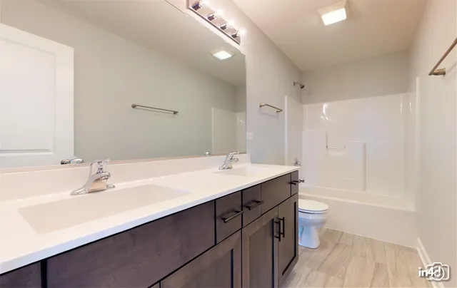 a bathroom with a double vanity sink a toilet and a mirror