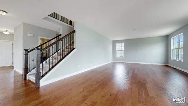 a view of an empty room with wooden floor and window
