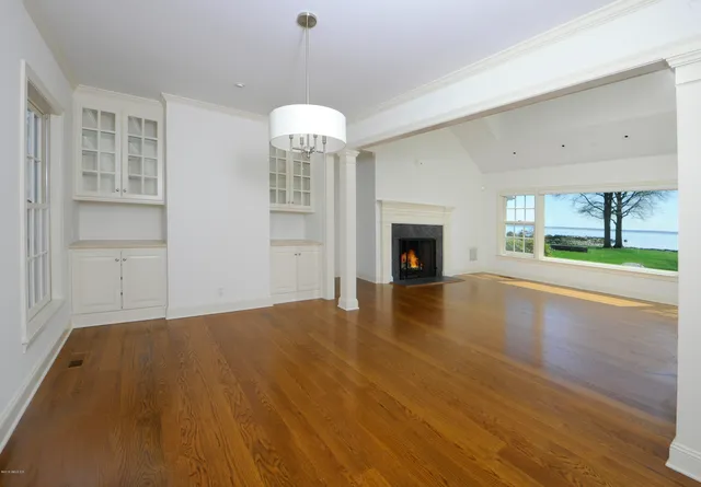 an empty room with wooden floor fireplace and windows