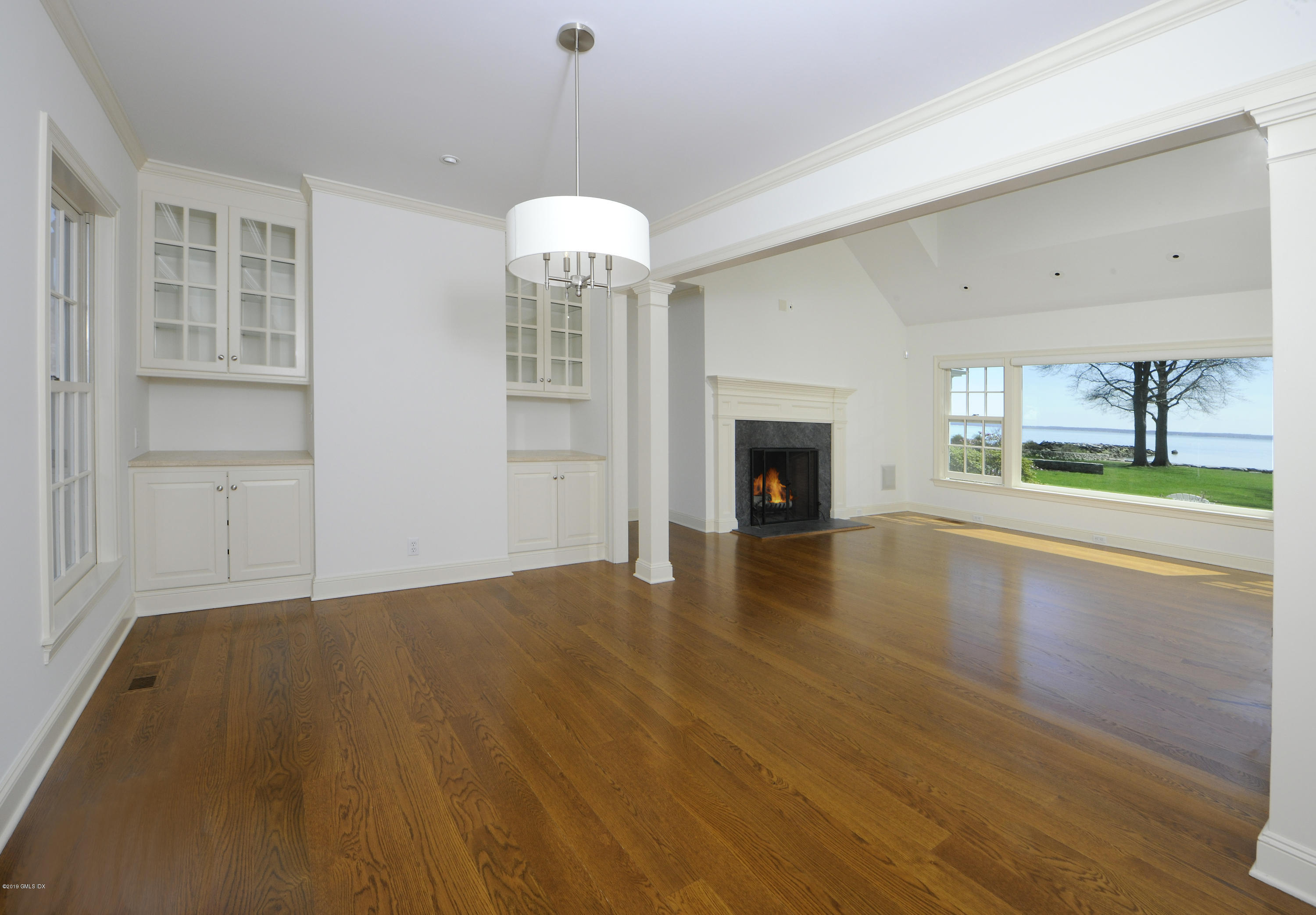 30 Rocky Point Road Old Greenwich, CT 06870 - Photo 9 of 29 an empty room with wooden floor fireplace and windows