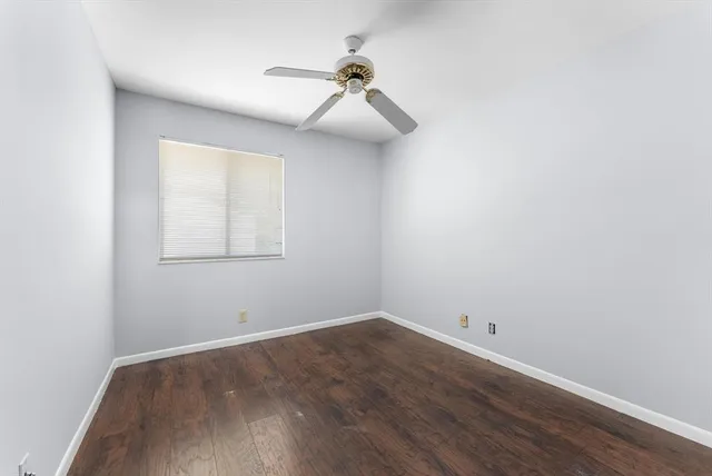 an empty room with wooden floor closet and windows