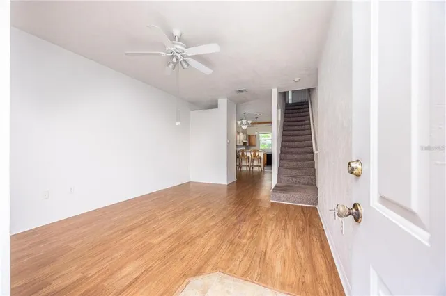 a view of a room with wooden floor and ceiling fan