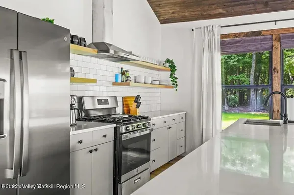 a kitchen with stainless steel appliances granite countertop a refrigerator a stove and a sink
