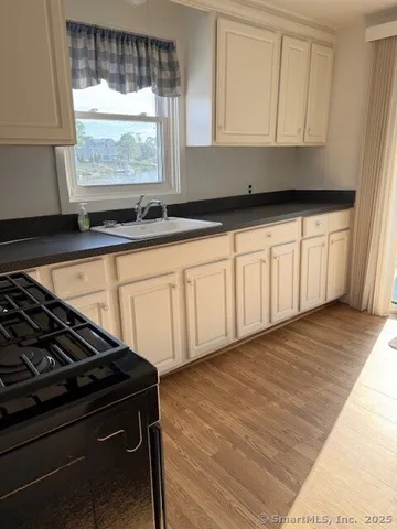 a kitchen with granite countertop white cabinets and a stove top oven