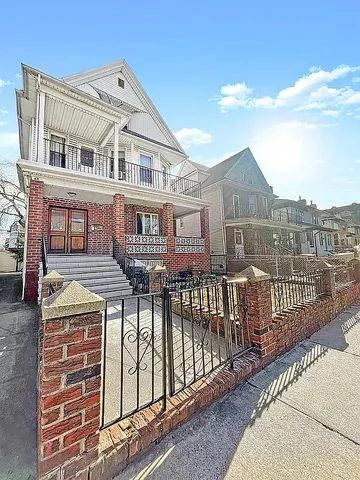 a view of a brick house with wooden fence