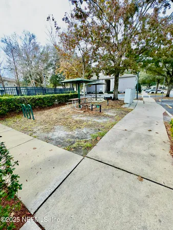 a view of a yard with plants and a barbeque